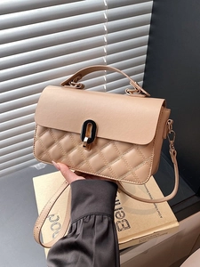 Retro apricot handbag with quilted stitching and gold oval clasp shown in hand