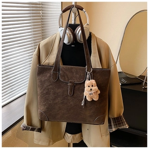 Detail of vintage brown tote bag showing contrast stitching and cute teddy bear charm