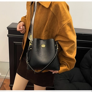 Detail of black lychee grain leather bucket bag with gold oval twist lock closure