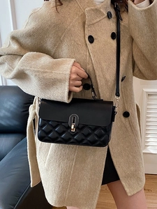 Classic black quilted leather handbag with gold clasp shown on a model's shoulder