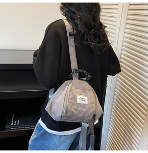 Detailed close-up of grey plaid canvas backpack with durable nylon texture and rope handle