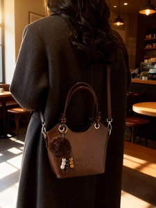 Vintage dark brown bucket bag with embossed logo and fuzzy pompom charm for women