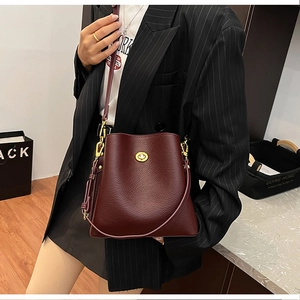 Detail of burgundy lychee grain leather bucket bag with gold hardware and shoulder strap