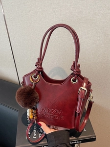 Retro burgundy bucket bag with glossy finish, pom-pom charm and adjustable strap