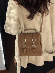 Retro brown faux suede backpack with metal buckles shown on model in warm knitwear
