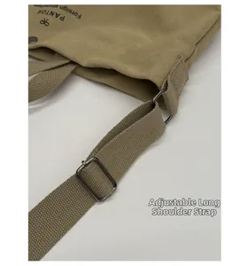 Detail of a khaki canvas bag with an adjustable long shoulder strap and metal buckle