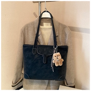 Detail of black vintage tote bag with white contrast stitching and plush bear charm