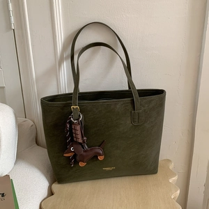 Detail of olive green suede tote bag featuring a cute dachshund leather charm and gold logo