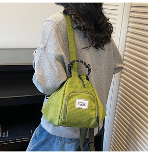 Rear view of green checkered canvas backpack worn by a model in a natural home setting