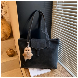 Detailed shot of retro tote bag with white stitching and cute teddy bear pendant decoration