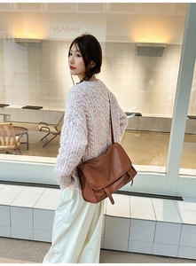 Brown vintage leather messenger bag worn over the shoulder by a model for a stylish look