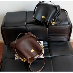 Detail of lychee pattern leather texture on black and dark brown bucket bags with gold locks