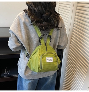 Detail of green plaid canvas backpack with unique triangle shape and woven handle