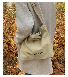 Close-up of canvas tote bag with black letter print and adjustable shoulder strap