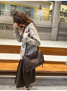 Side view of a vintage dark brown satchel bag worn by a model in outdoor setting