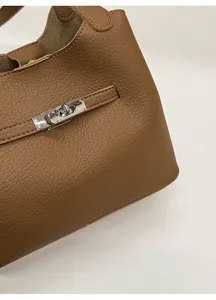 Macro shot of brown lychee texture PU leather and metal lock buckle on bucket bag