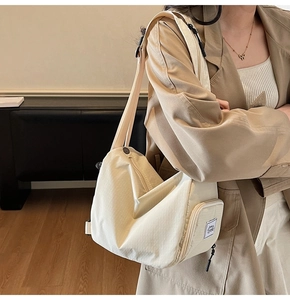 Detail view of the side zipper pocket and logo label on a beige canvas travel backpack