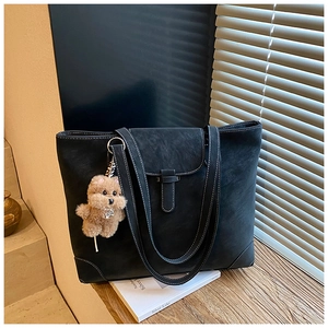 Detail of matte black tote bag featuring white contrast stitching and puppy bag charm