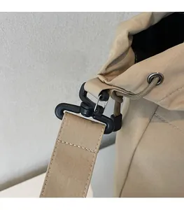Detail showing the black swivel hook and reinforced shoulder strap on a khaki canvas bag