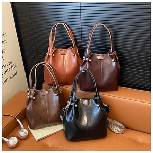 Detailed view of bucket bags in four retro colors with polished faux leather and studs