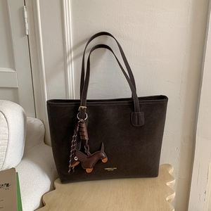Close-up of deep brown tote bag with leather dachshund charm and chocolate deco accessory