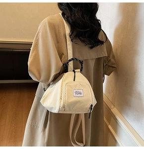 Detail of the woven handle and square zipper pocket on beige canvas backpack