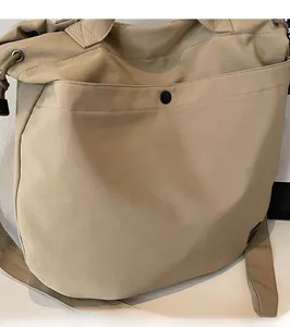 Detail view of the khaki lightweight nylon tote bag featuring front pocket and metal snap