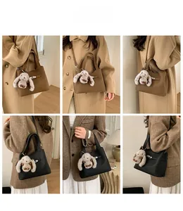 Detail showing pebbled leather bucket bag with silver lock and plush bunny charm