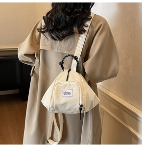 Detail of off-white triangular mini backpack with Muran Bags label and woven handle