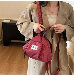 Detail shot of the red plaid canvas mini backpack with Muman Bags label and strap