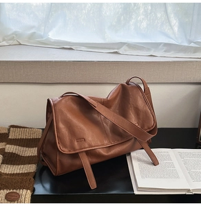 Detailed view of a vintage brown messenger bag with smooth synthetic leather texture