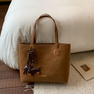 Detailed view of brown suede tote bag featuring a cute dachshund and chocolate charm