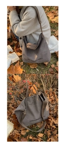 Detail of dark grey canvas tote bag with logo on a bed of autumn fallen leaves