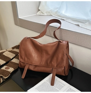 Detail of dark brown vintage messenger bag with soft texture and adjustable strap