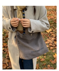 Close-up of a charcoal canvas tote bag with snap button on golden autumn leaves