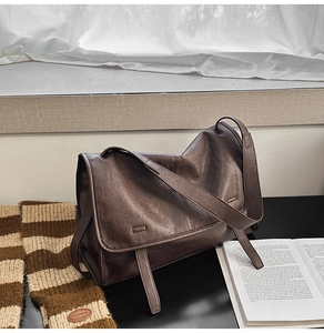 Close-up of vintage dark brown faux leather shoulder bag with textured pleats on a desk