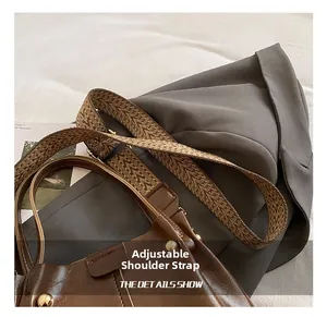 Close-up of brown oiled leather bucket bag with vintage geometric wide fabric strap