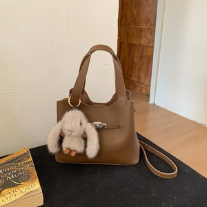 Close-up of brown pebbled leather bucket bag with silver twist lock and bunny charm