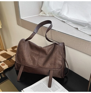 Detailed close-up of dark brown vintage messenger bag with leather strap and buckle details