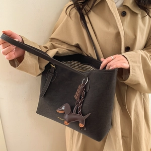 Detail view of large brown suede tote bag with dog charm and interior stripe lining