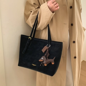 Detail of black suede leather tote with adjustable strap and designer animal charms