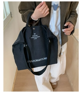 Detail of durable black canvas tote bag with white lettering and adjustable wide shoulder strap