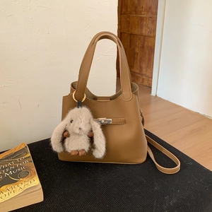 Detailed view of a brown pebbled leather bucket bag with a silver twist lock and bunny charm