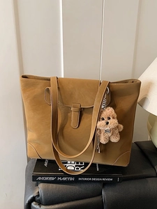 Retro brown large capacity tote bag with plush dog charm on a leather sofa