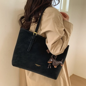 Detail of black leather tote bag with gold lettering and brown dachshund pendant