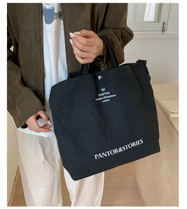 Detail of black canvas tote bag showing white Pantor text print and ribbon logo