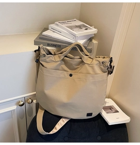 Detail of khaki canvas bag showing black metal snap pocket and square decorative label