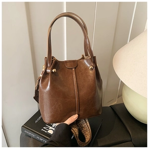 Detail of vintage brown leather bucket bag with gold hardware and woven jacquard strap