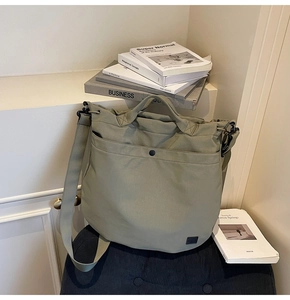 Detail view of olive green canvas tote bag showing the snap pocket and wide shoulder strap