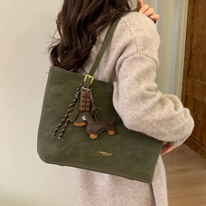 Detail of dark green tote bag with cute chocolate and dachshund charms on shoulder